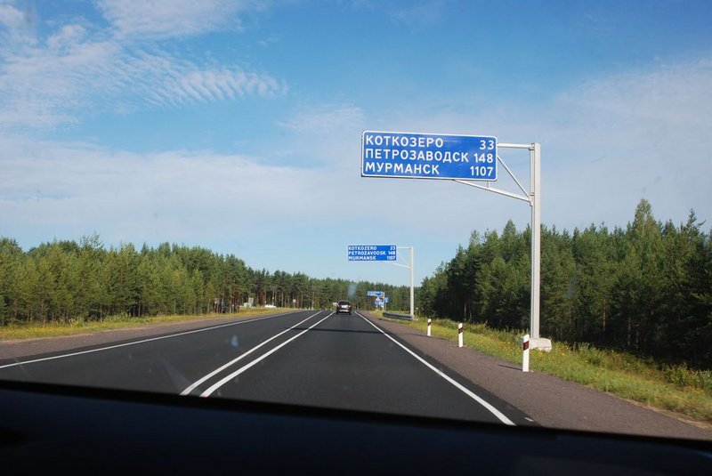 11:20. Остановились перекусить в придорожном кафе у поворота на Пряжу. Здесь мы уже останавливались три раза в 2010-м. Как и в 2010-м фотографируем машину на фоне хорошо знакомого нам дорожного указателя. Типа традиция.&nbsp;