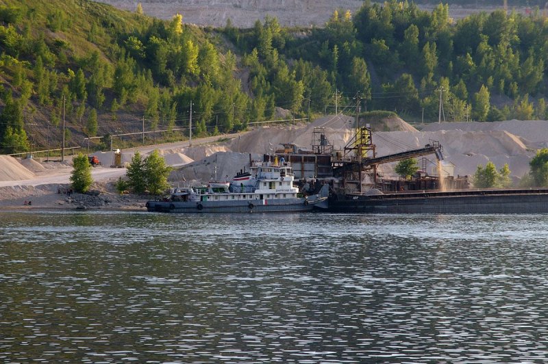 Слышу сзади нарастающий шум судна. Оглядываюсь. Сзади идёт
буксир, толкая пустую баржу. Участники гонки расступились&nbsp; и &nbsp;освободили
ему коридор шириной 50—60 м, но на фарватере &nbsp;всё равно всё плотно. На буксире включается
сирена и по громкоговорителю над Волгой разносится такой 3-х этажный мат! Так
виртуозно материться могут только &nbsp;капитаны волжских буксиров. Нам приказывают
немедленно&nbsp; уйти на три буквы с
фарватера, а иначе он сейчас вызовет полицию и нас всех повяжут как опасных
террористов. Гонка на несколько секунд останавливается, пропуская вперёд
бравого капитана, который еще несколько минут вспоминает наших матерей и что то про лиц нетрадиционной сексуальной ориентации и&nbsp; буксир,
пыхтя выхлопом дизеля, &nbsp;гордо идет
дальше. Проходим посёлок &nbsp;Ширяево,где великий русский художник Репин писал своих "Бурлаков на Волге"

