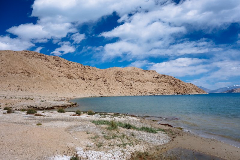 К сожалению, и в этот в залив прорывались
из-за хребта очень сильные порывы ветра, причем обрушивались они с совершенно
разных направлений. Наконец нашел прикрытую от ветра с трех сторон щель между
камнями, где удобнее готовить обед, быстро поел и в 15:47 вышел на воду.
Сегодня была цель – дойти к вечеру до
ручья или реки, в которых точно есть вода. Дальнейший путь шел по одному
сценарию – я входил в очередной залив с южного края против ветра, догребал
почти до берега, поворачивал направо и выходил по ветру с северного края.
Несмотря на сильный ветер, волна была еще терпимая, не успевала набрать высоту.
Пройдя так пять мысов я зашел в залив, в который открывалось устье реки.
Несколько десятков метров греб по устью, преодолевая течение, после чего в
16:54 вылез и вытащил байдарку на прибрежную траву.
Река хоть и с узким руслом, но весьма
полноводная, берет свое начало от ледников хребта Каракуль. К сожалению, и в этот в залив прорывались
из-за хребта очень сильные порывы ветра, причем обрушивались они с совершенно
разных направлений. Наконец нашел прикрытую от ветра с трех сторон щель между
камнями, где удобнее готовить обед, быстро поел и в 15:47 вышел на воду.
Сегодня была цель – дойти к вечеру до
ручья или реки, в которых точно есть вода. Дальнейший путь шел по одному
сценарию – я входил в очередной залив с южного края против ветра, догребал
почти до берега, поворачивал направо и выходил по ветру с северного края.
Несмотря на сильный ветер, волна была еще терпимая, не успевала набрать высоту.
Пройдя так пять мысов я зашел в залив, в который открывалось устье реки.
Несколько десятков метров греб по устью, преодолевая течение, после чего в
16:54 вылез и вытащил байдарку на прибрежную траву.
Река хоть и с узким руслом, но весьма
полноводная, берет свое начало от ледников хребта Каракуль.